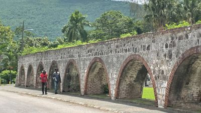 Two Caribbean men walking along an arched old stone bridge