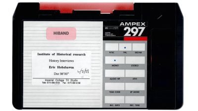 A vintage AMPEX 297 U-matic SP videocassette with a red and white label marked “HIBAND.” A printed sticker reads "Institute of Historical Research – History Interviews – Eric Hobsbawm – Dur 38'00” dated 4/7/88. It was produced by the Imperial College TV Studio, with contact details at the bottom. The cassette's right side displays format options such as NTSC, PAL, MONO, and STEREO.